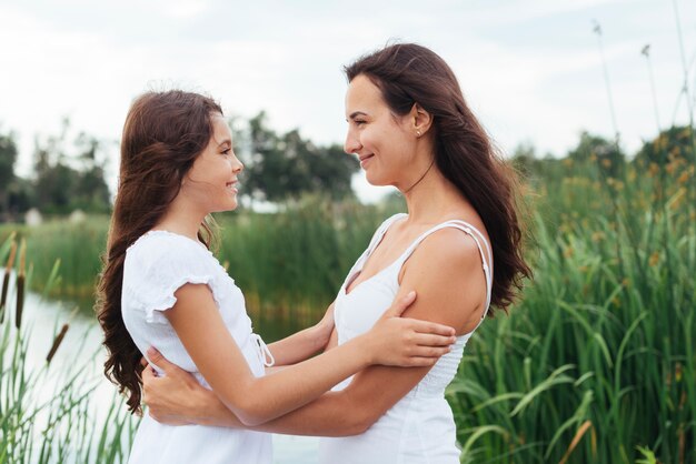 Mother and daughter embracing by the lake