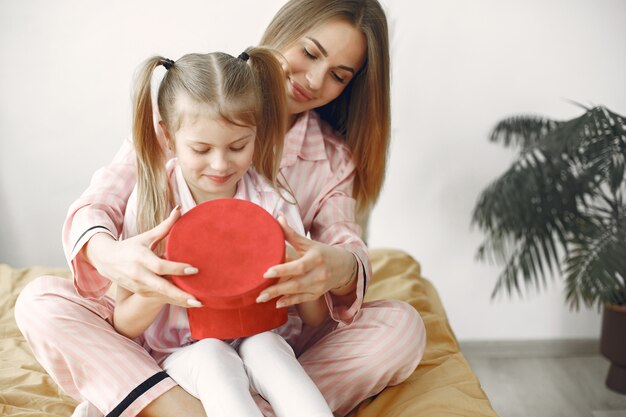 Mother and daughter enjoying on the bed. Holding red gift box. Mother's Day.