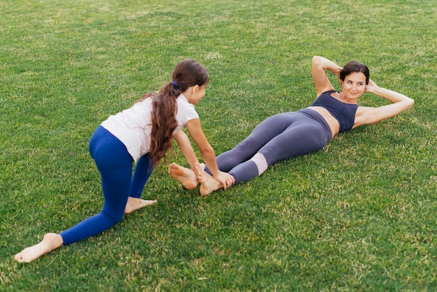 Mother and daughter exercising on green grass