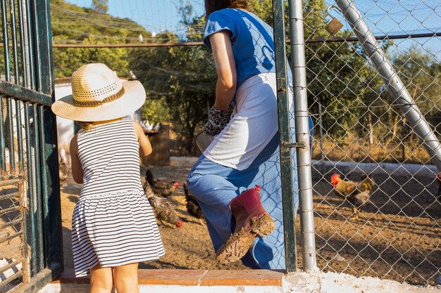 Mother and daughter feeding chickens in the farm