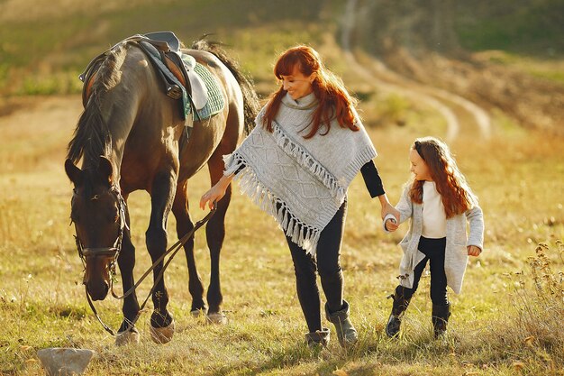 Mother and daughter in a field playing with a horse