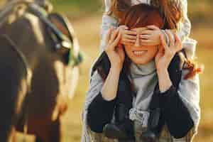 Free photo mother and daughter in a field playing with a horse