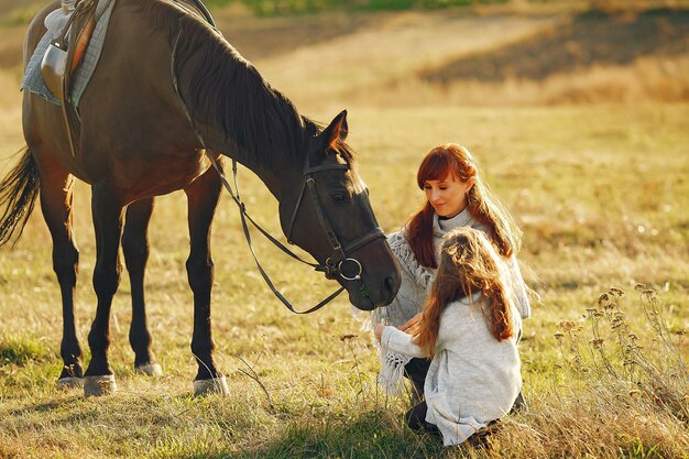 Mother and daughter in a field playing with a horse