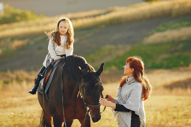 Мать и дочь в поле, играя с лошадью
