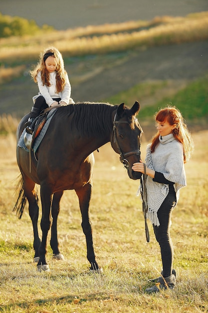 Mother and daughter in a field playing with a horse