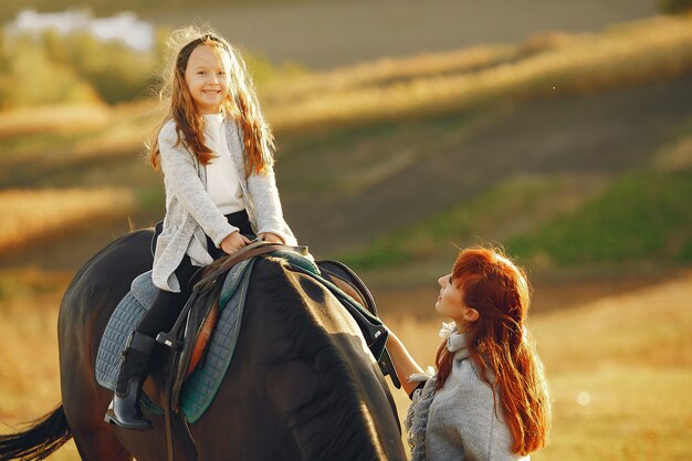 Mother and daughter in a field playing with a horse