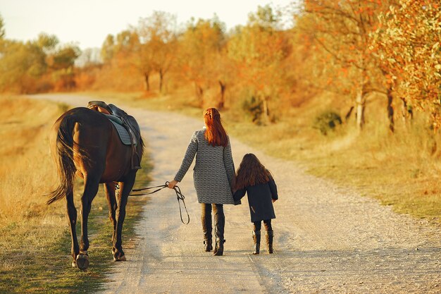 Мать и дочь в поле, играя с лошадью