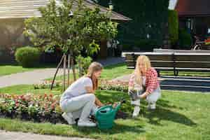 Free photo mother and daughter in gloves planting flowers at garden