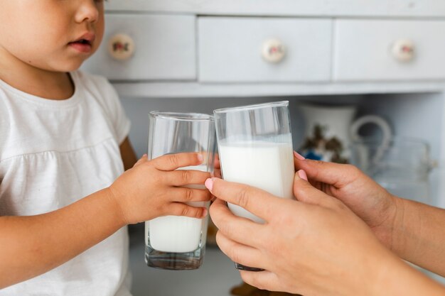 Mother and daughter hands holding gasses of milk