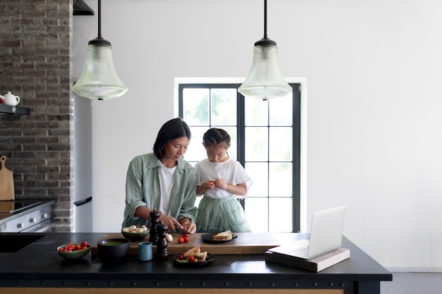 Free photo mother and daughter having a video call from their kitchen