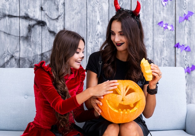 Mother and daughter holding carved pumpkin for halloween