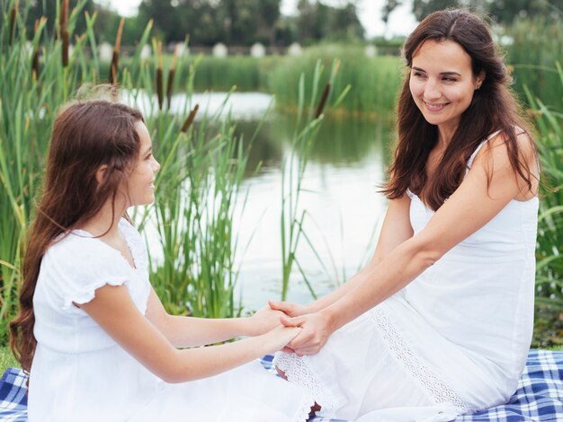 Mother and daughter holding hands by the lake