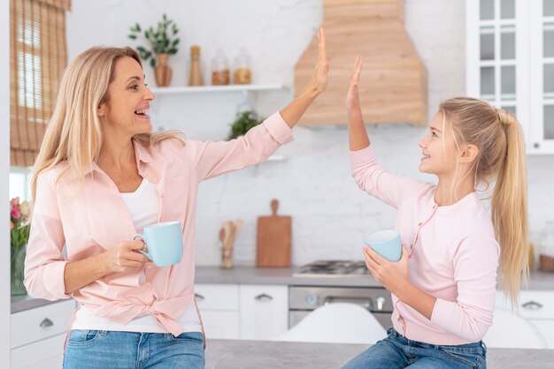 Mother and daughter holding mugs and saluting