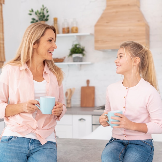 Mother and daughter holding mugs