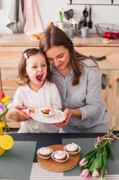 Mother and daughter holding plate with cupcake