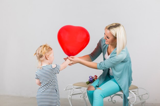 Mother and daughter holding red heart balloon