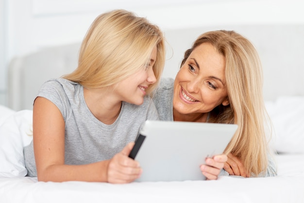 Mother and daughter holding tablet and looking at each other