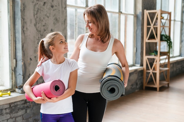 Mother and daughter holding yoga mats