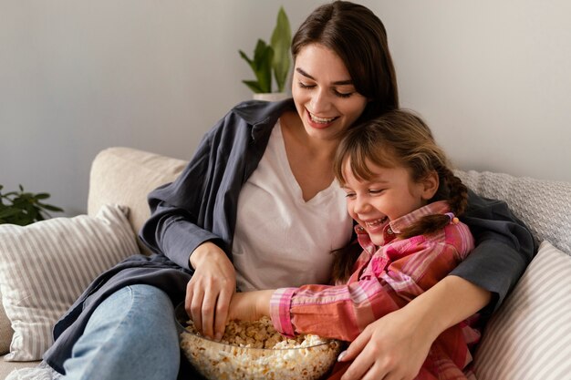 Mother and daughter at home eating popcorn