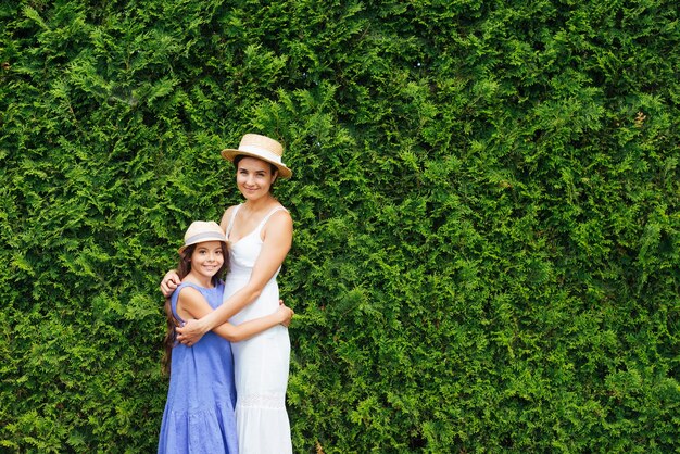 Mother and daughter hugging in front of bushes