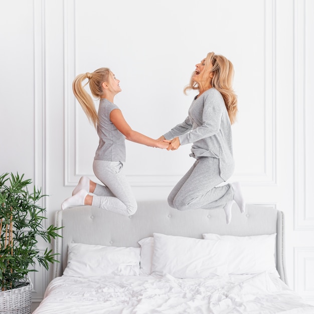 mother and daughter jumping in bed