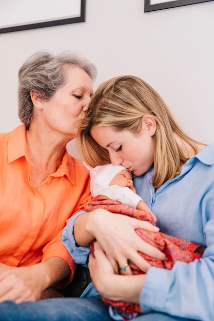 Mother and daughter kissing baby