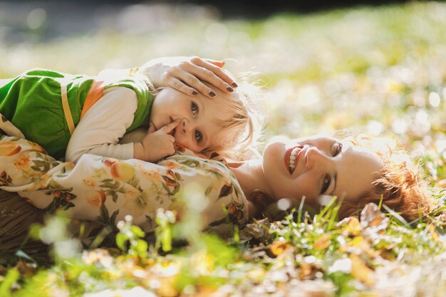 The mother and daughter lie on the grass