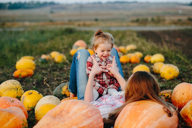 Mother and daughter lie between pumpkins on the field, Halloween eve