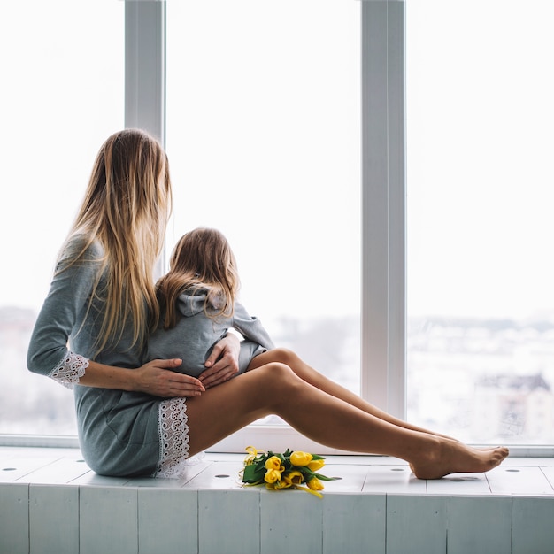 Free photo mother and daughter looking through window