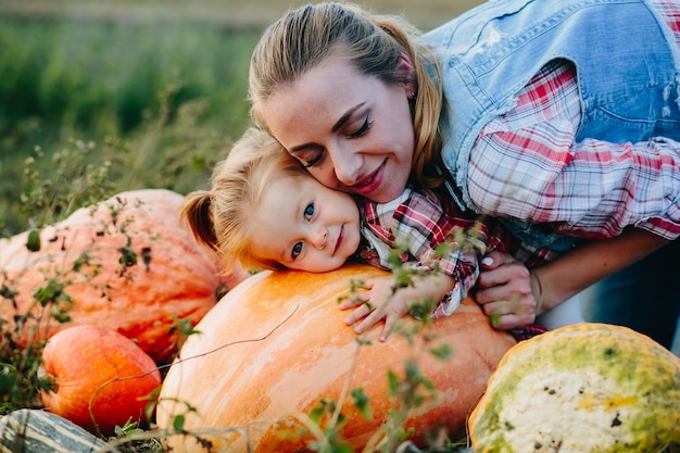 Free photo mother and daughter lying together on pumpkins