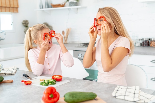 Madre e figlia che fanno i fronti divertenti con i peperoni