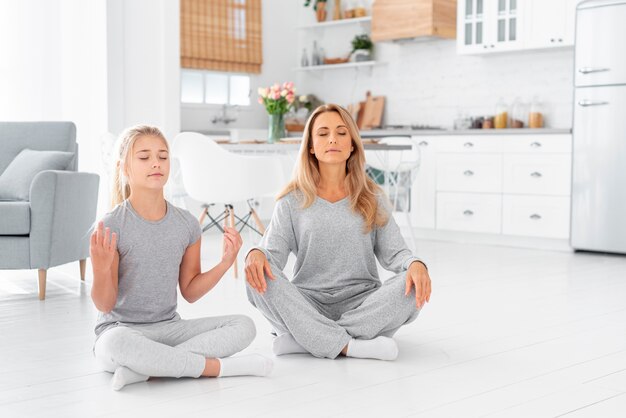 Mother and daughter meditating indoor