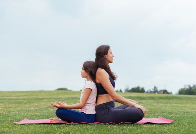 Мать и дочь медитируют на свежем воздухе