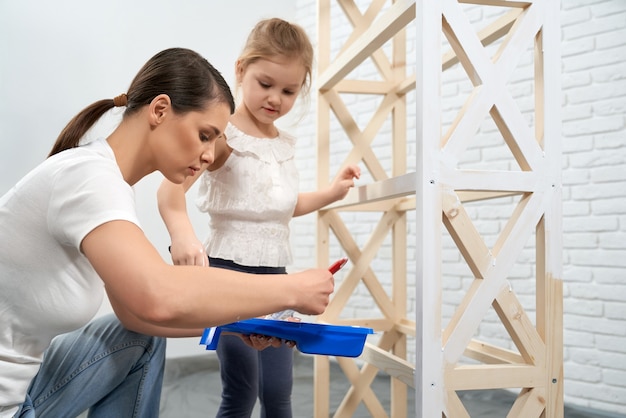 Free photo mother and daughter painting wooden rack