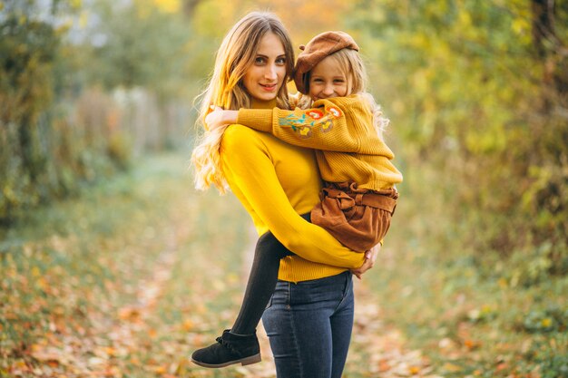 Mother and daughter in park full of leaves