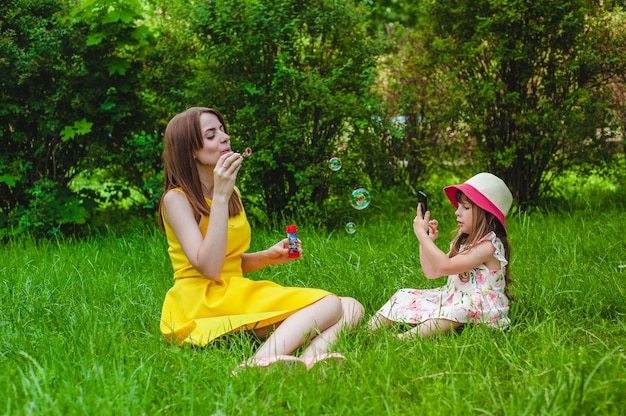Мать и дочь играет с мыльными пузырями