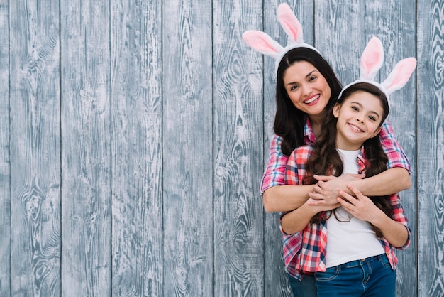Mother and daughter posing in front of wooden gray backdrop