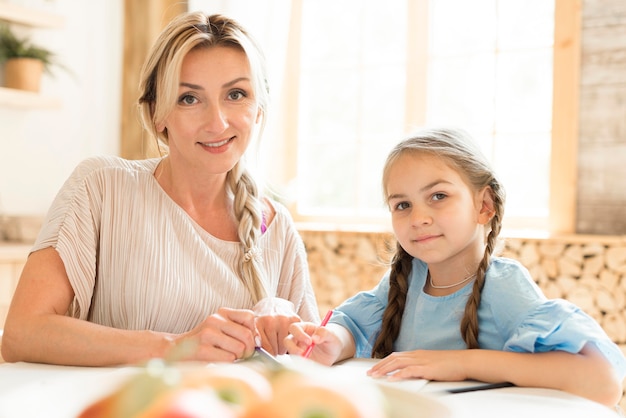 Free photo mother and daughter posing while doing homework together