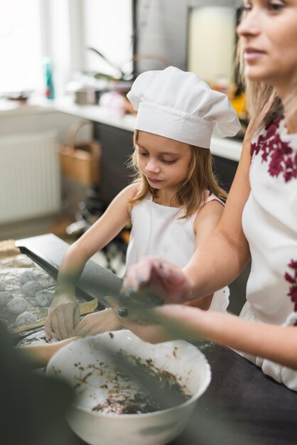 Mother and daughter preparing cookies in kitchen