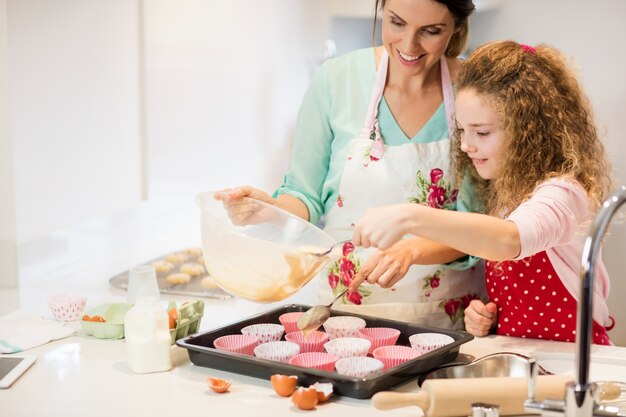 Мать и дочь приготовления кекс на кухне