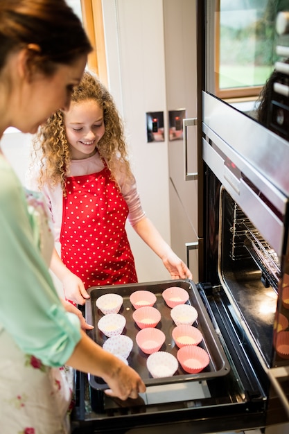 Mother and daughter preparing cupcake in kitchen
