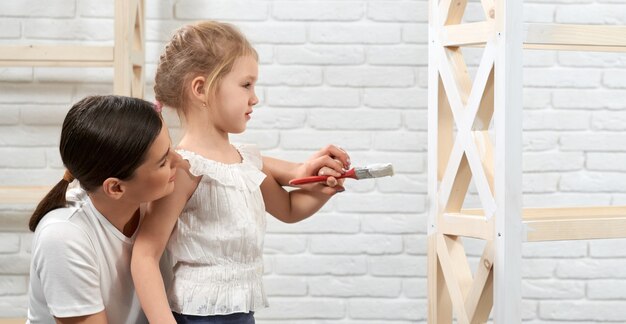 Mother and daughter in process of painting rack at home