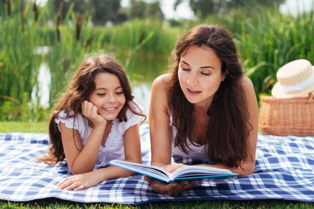 Mother and daughter reading book outdoors