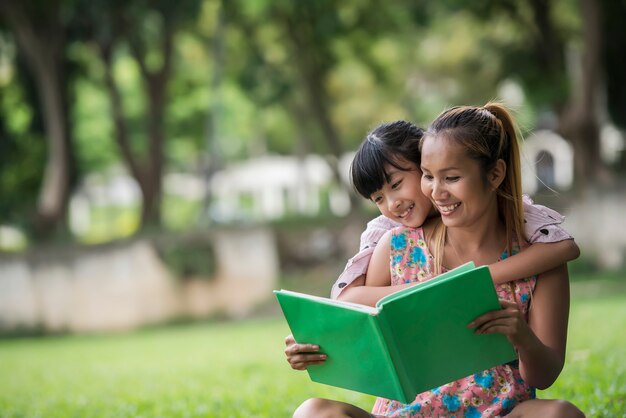 Мать и дочь читают сказку своей дочери в парке