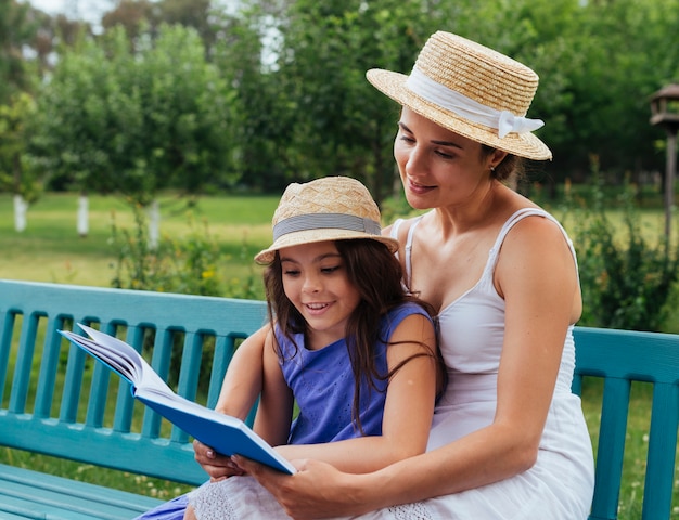 Free photo mother and daughter reading together on bench