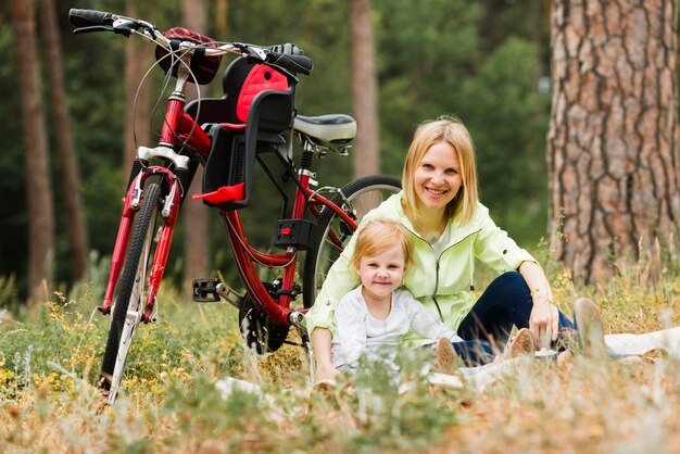 Мать и дочь отдыхают рядом с велосипедом