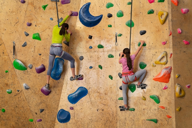 Mother and daughter rock climbing together indoors at the arena