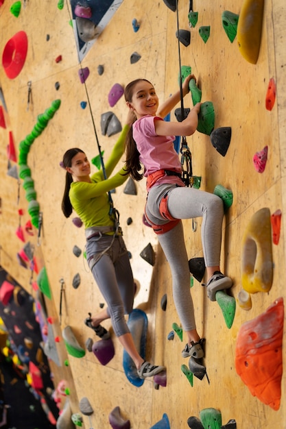 Mother and daughter rock climbing together indoors at the arena