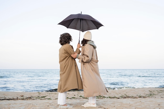 우산 아래 해변에서 부드러운 순간을 공유하는 엄마와 딸