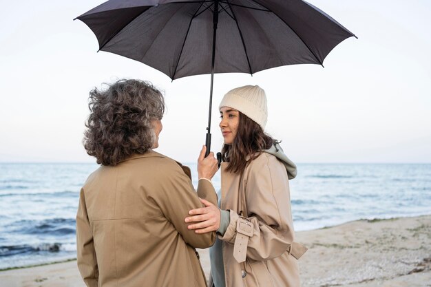 우산 아래 해변에서 부드러운 순간을 공유하는 엄마와 딸